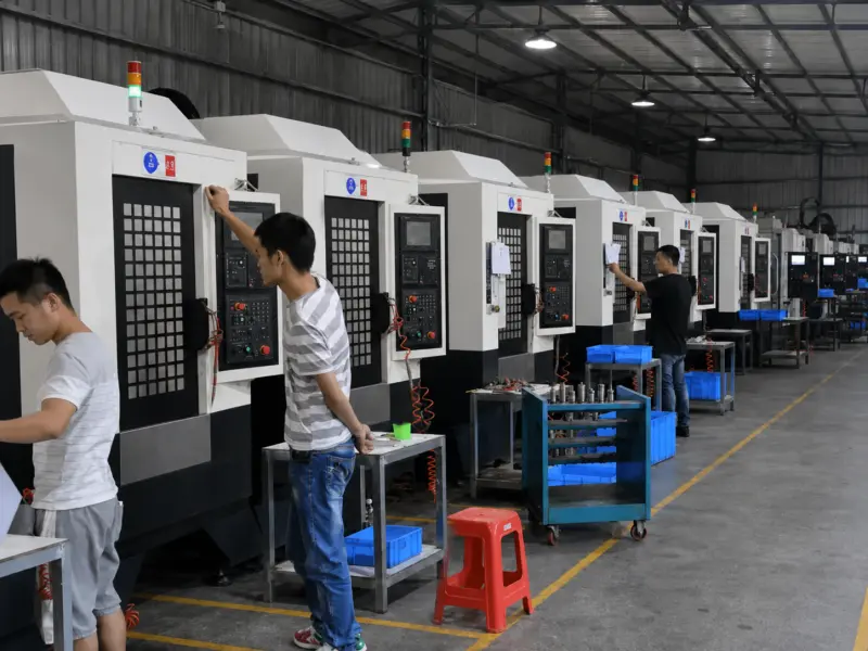 CNC machining production line under gray metal shed roof with operators in different casual clothing