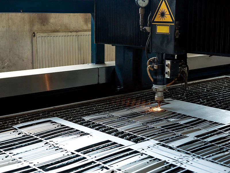 Laser cutting head processing sheet metal panels on a fabrication machine